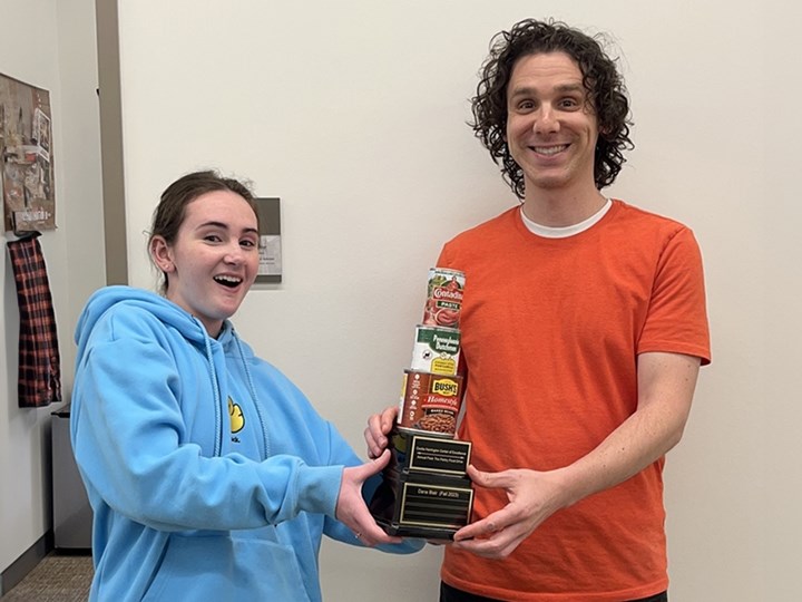 Greg Stine, team captain for the Fulbright Advising Team, accepts the food drive trophy from Mara Privette, a CORD Board member.
