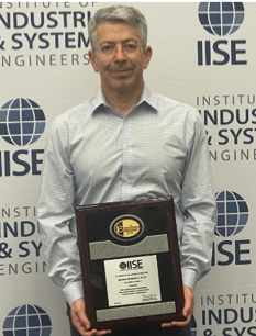 professor Burak Eksioglu holds an plaque recognizing his leadership