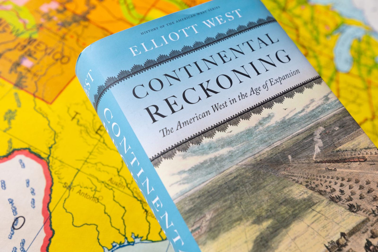 the cover of the book Continental Reckoning as it sits atop a map of the west