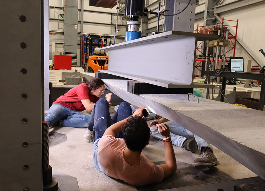 graduate students examine a concrete beam for stress fractures