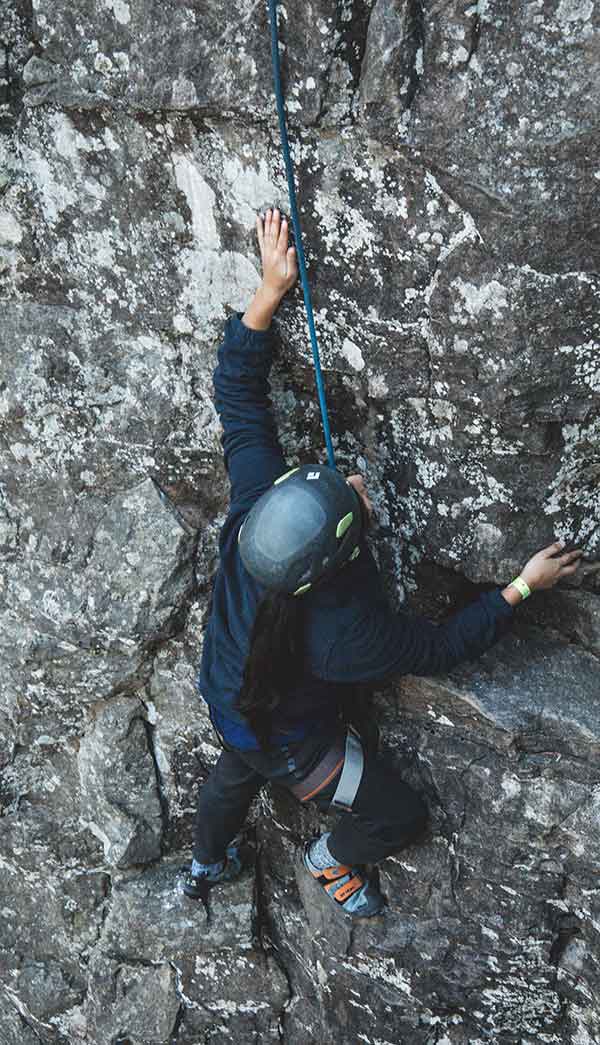 A rock climber looks for hand holds