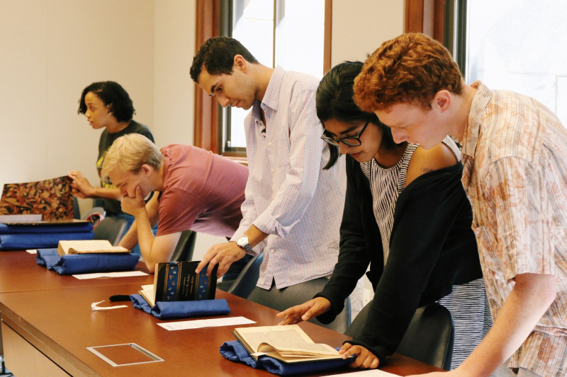 Undergraduate students work directly with rare books and manuscripts at a long table