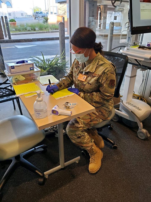 Ayana Thompson in fatigues and face mask at a desk preparing materials for testing.