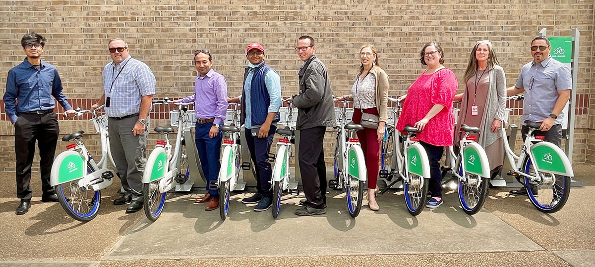 Participating partners in the research program stand next to share bicycles