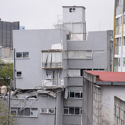 A building in Mexico showing the collapse of upper stories onto a lower story during an earthquake.