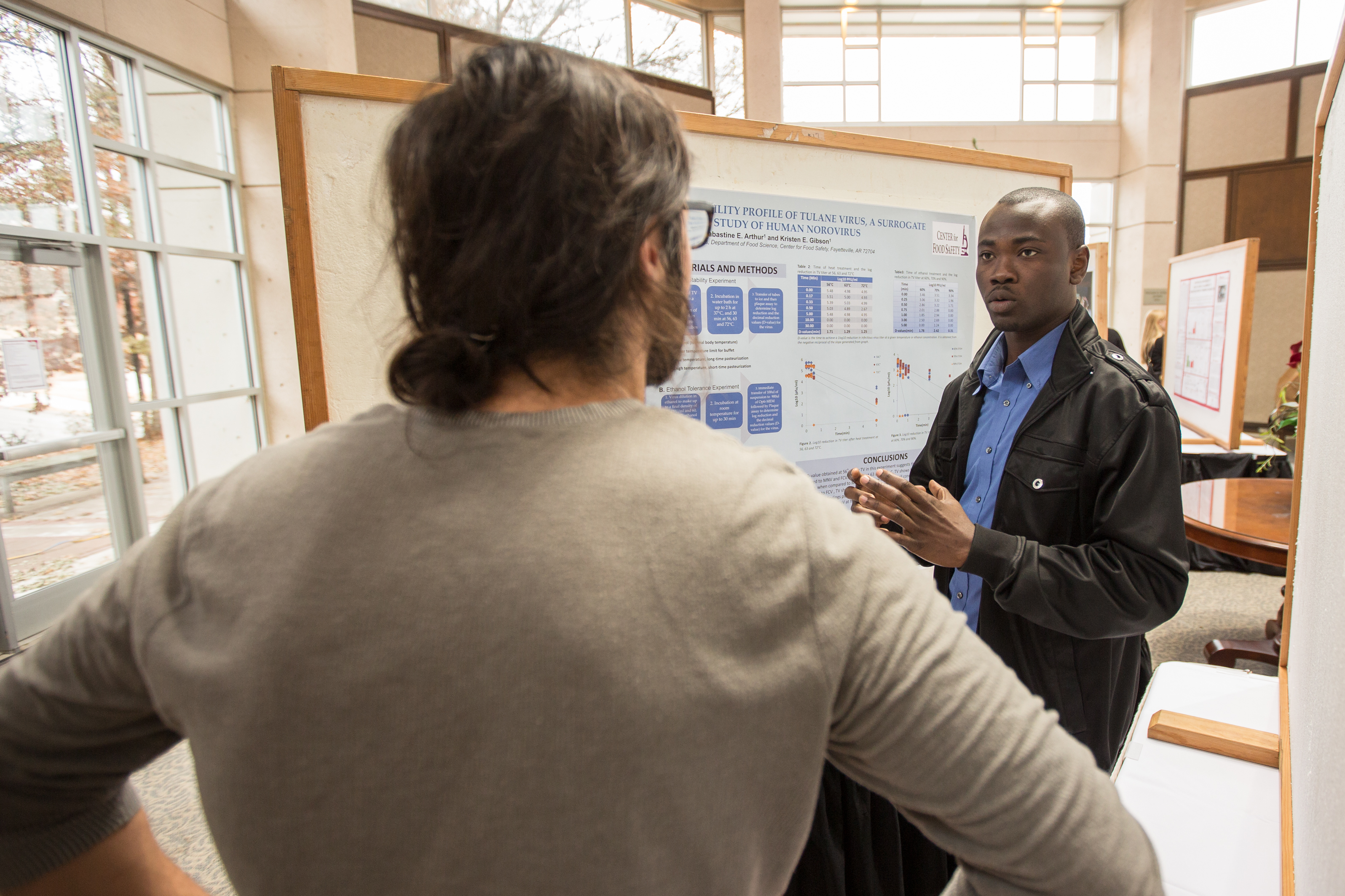 Sabastine Arthur, a master's student in cell and molecular biology, explains his research prior to Tuesday's ceremony honoring winners in the University of Arkansas' annual graduate student poster competition. Arthur finished first in the food science category. Photo by Matt Reynolds, University of Arkansas.