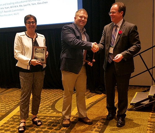 Dennis Beck, center, is congratulated by Eugene Kowch, president of the Association for Educational Communications and Technology. Mahnaz Moallem, left, of the University of North Carolina Wilmington, also received an award.