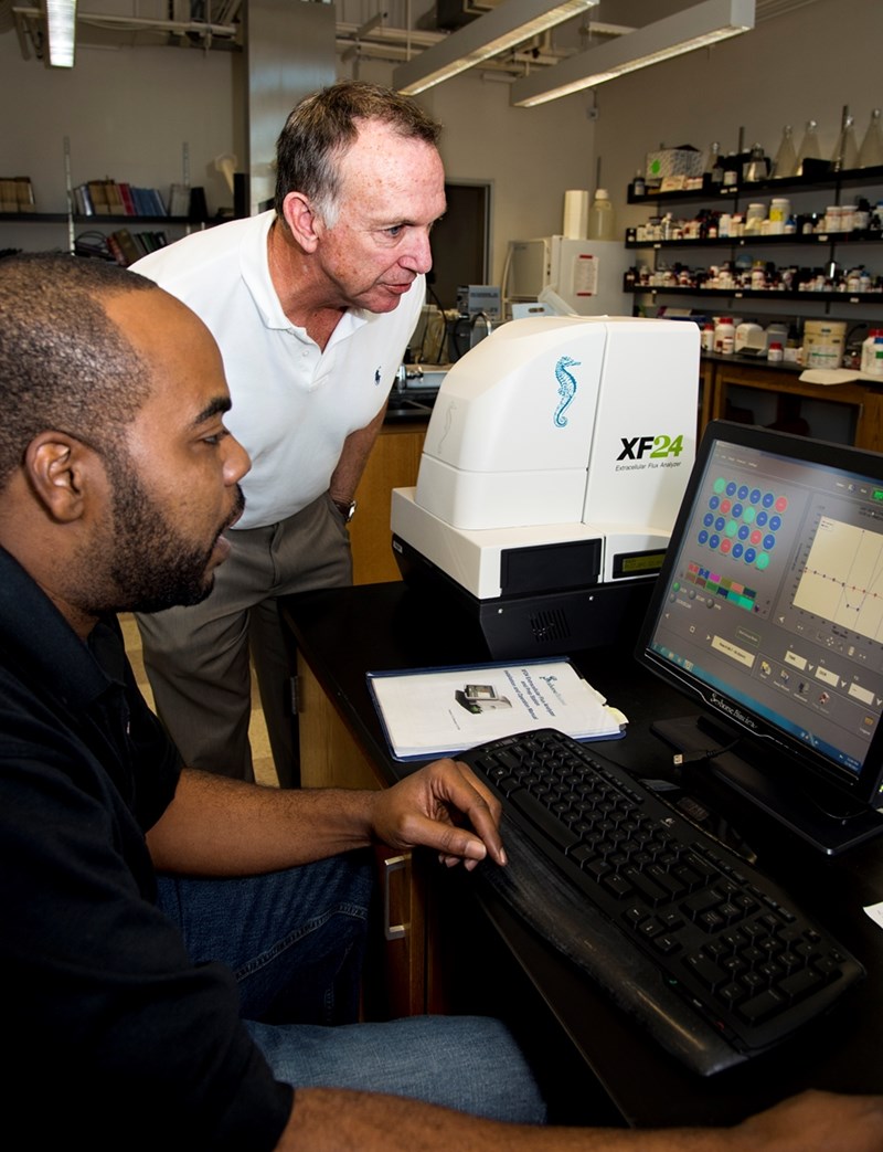 Poultry scientist Walter Bottje and research associate Kentu Lassiter examine mitochondrial function analysis data used in their research on oxidative stress in poultry. The Extracellular Flux Analyzer (dubbed the &quot;flux capacitor&quot;) chemically dissects and analyzes several aspects of mitochondrial function.