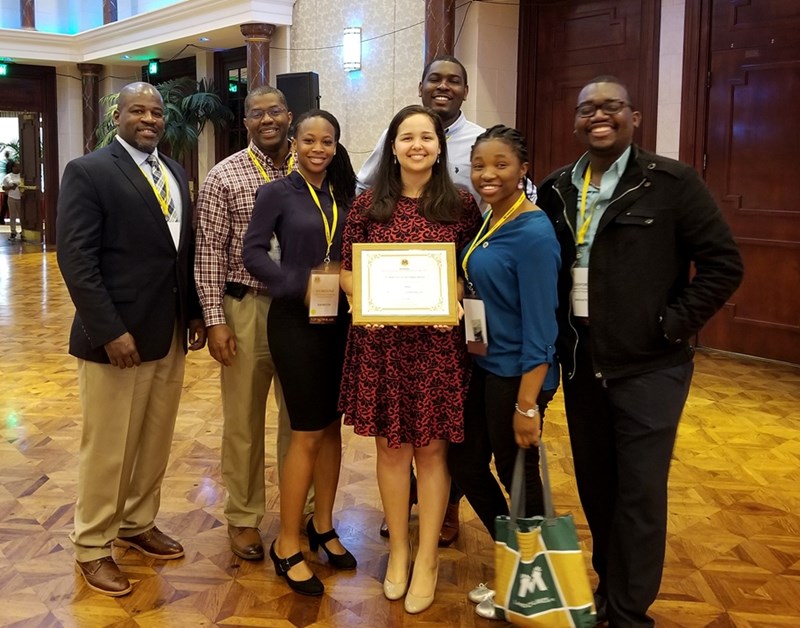 Karli Moore, center with award, and the U of A contingent at the Minorities in Agriculture, Natural Resources and Related Sciences annual meeting, including Bumpers College dean Deacue Fields III (left), and agricultural economics and agribusiness associate professor and graduate program coordinator Daniel Rainey (second from left).