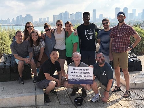 Doctoral students in education policy gather with faculty guides in front of the Tel Aviv coast and skyline.