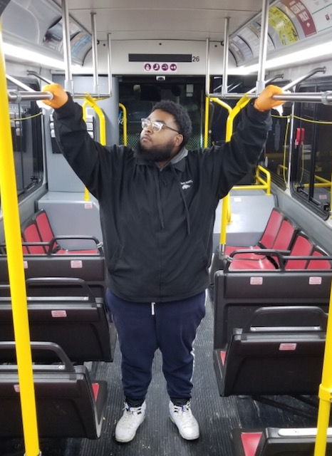 Dwayne Barber wipes the hand rails with sanitary wipes. He has been detailing buses for Razorback Transit for almost a year.