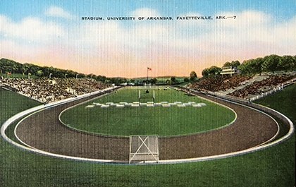 A post card from about 1950 shows Razorback Stadium looking south with a track, bleachers and a press box above the west side.