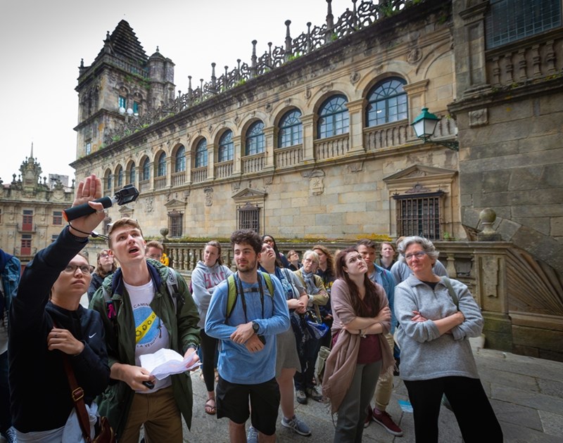 Les étudiants honorifiques et la doyenne Lynda Coon discutent de la sculpture du portail à la cathédrale de Saint-Jacques-de-Compostelle, lors d'un cours de passeport spécialisé qui a visité des sites le long du chemin de pèlerinage du Camino de Santiago à travers la France et l'Espagne.