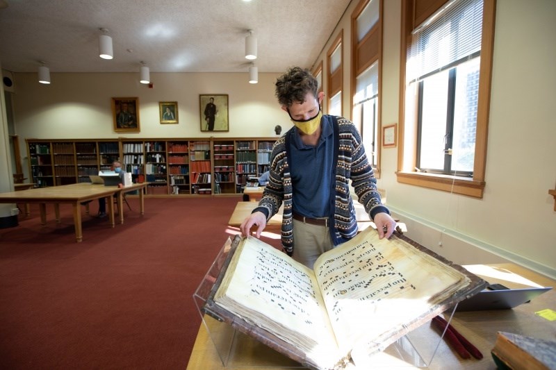 2021-22 Long-Term Fellow Aaron Hyman studies an 18th-century choirbook from the Newberry collection. Source of Photo: Newberry.org.