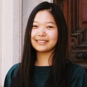 K-Ming Chang in a dark green sweater in front of a wooden door.