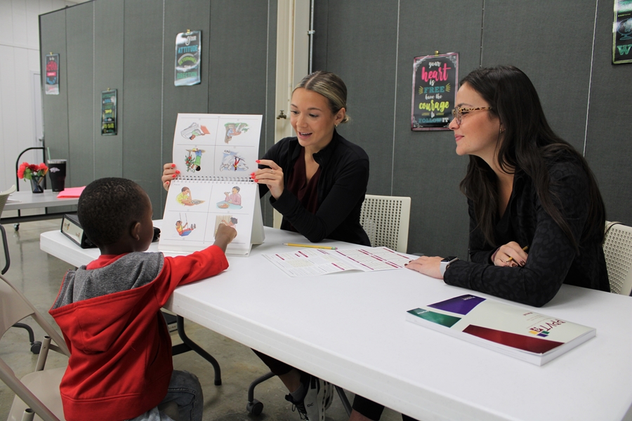 Communication Sciences and Disorders graduate students Addison Rogers (left) and Maddox McIntire evaluate the language, motor, and vocabulary skills of a child who attends Head Start in Fayetteville.
