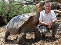 Professor William F. McComas kneels next to a tortoise during a visit to the Galápagos Islands.