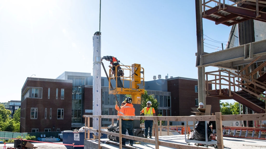 Construction workers secure the first column of cross-laminated timber in the new I³R building.