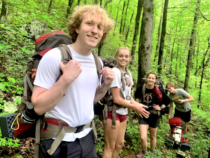 Students enrolled in the outdoor leadership minor pause for a break during an outdoor living skills backpacking trip.